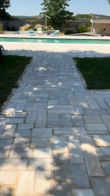 Camminamento in lastre di pietra naturale tra il prato e il bordo di una piscina