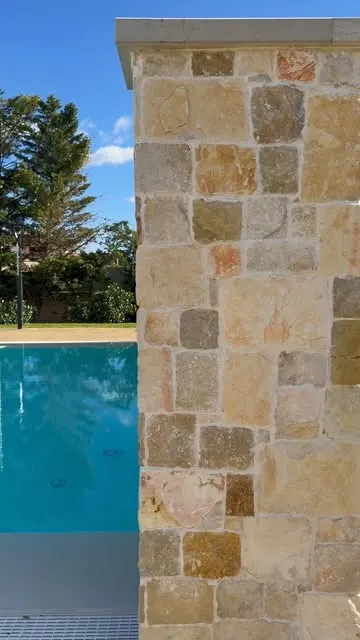 Muro rivestito in conci di pietra irregolari accanto a una piscina